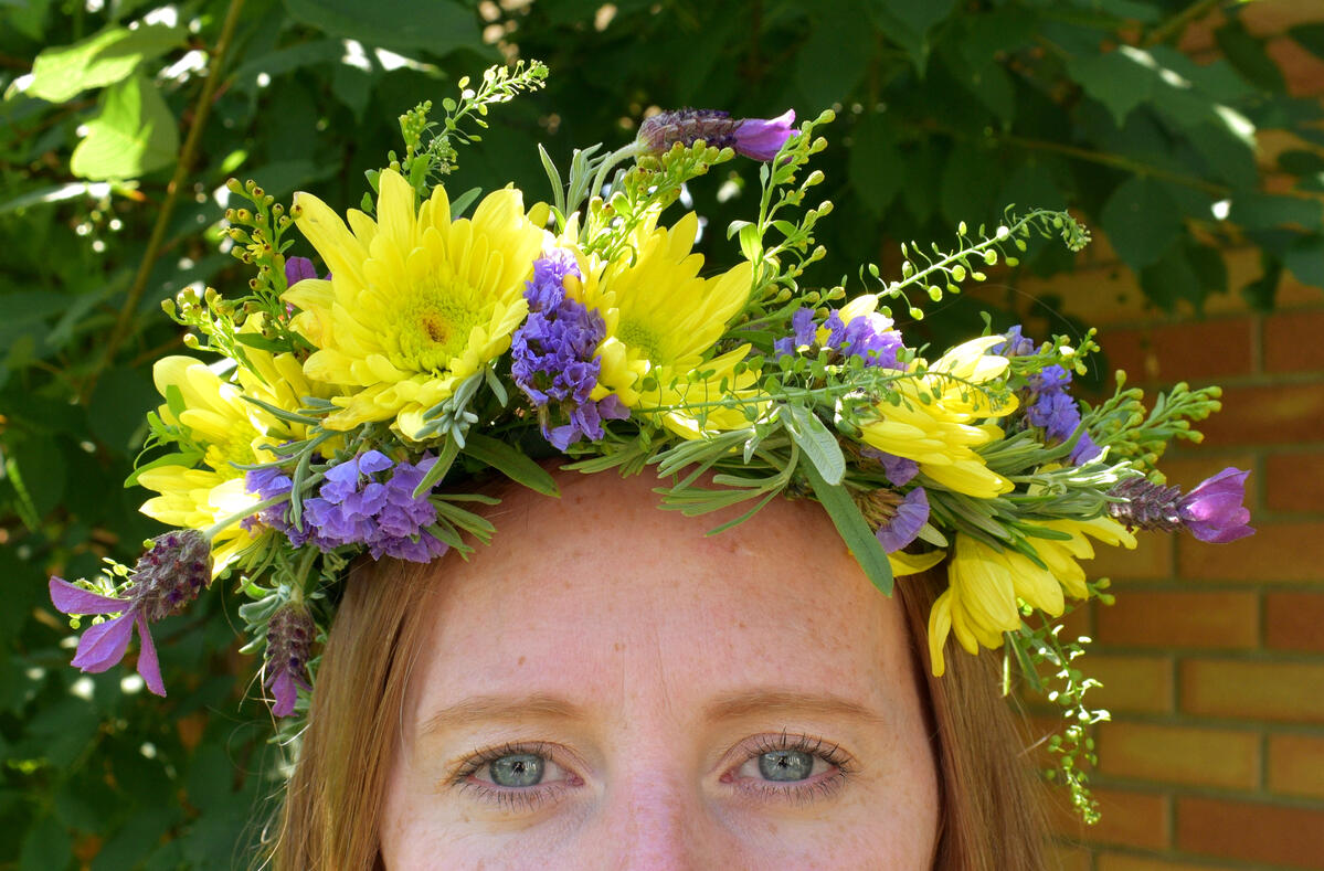 Floral Crown A woman, fromthe eyes up, wearing a floral crown.