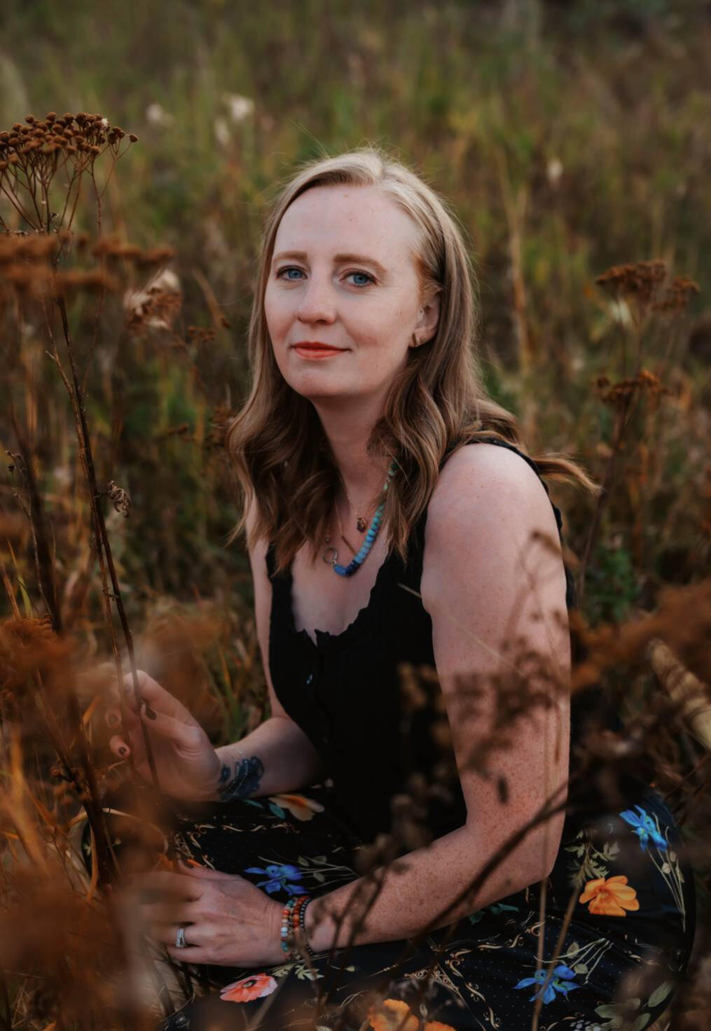 Meet Lauren A woman sitting amongst grasses.