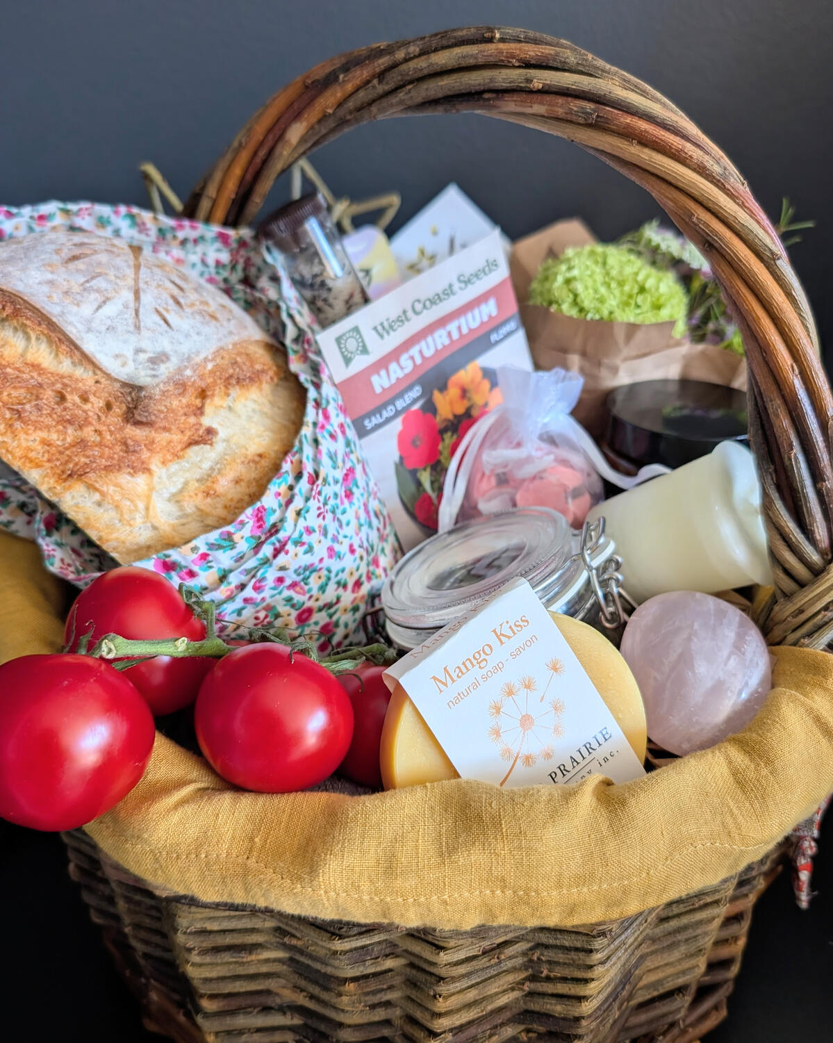 Gathering Table Basket WIllow basket full of the collected items, tomatoes, bread, soap, candles, flowers.