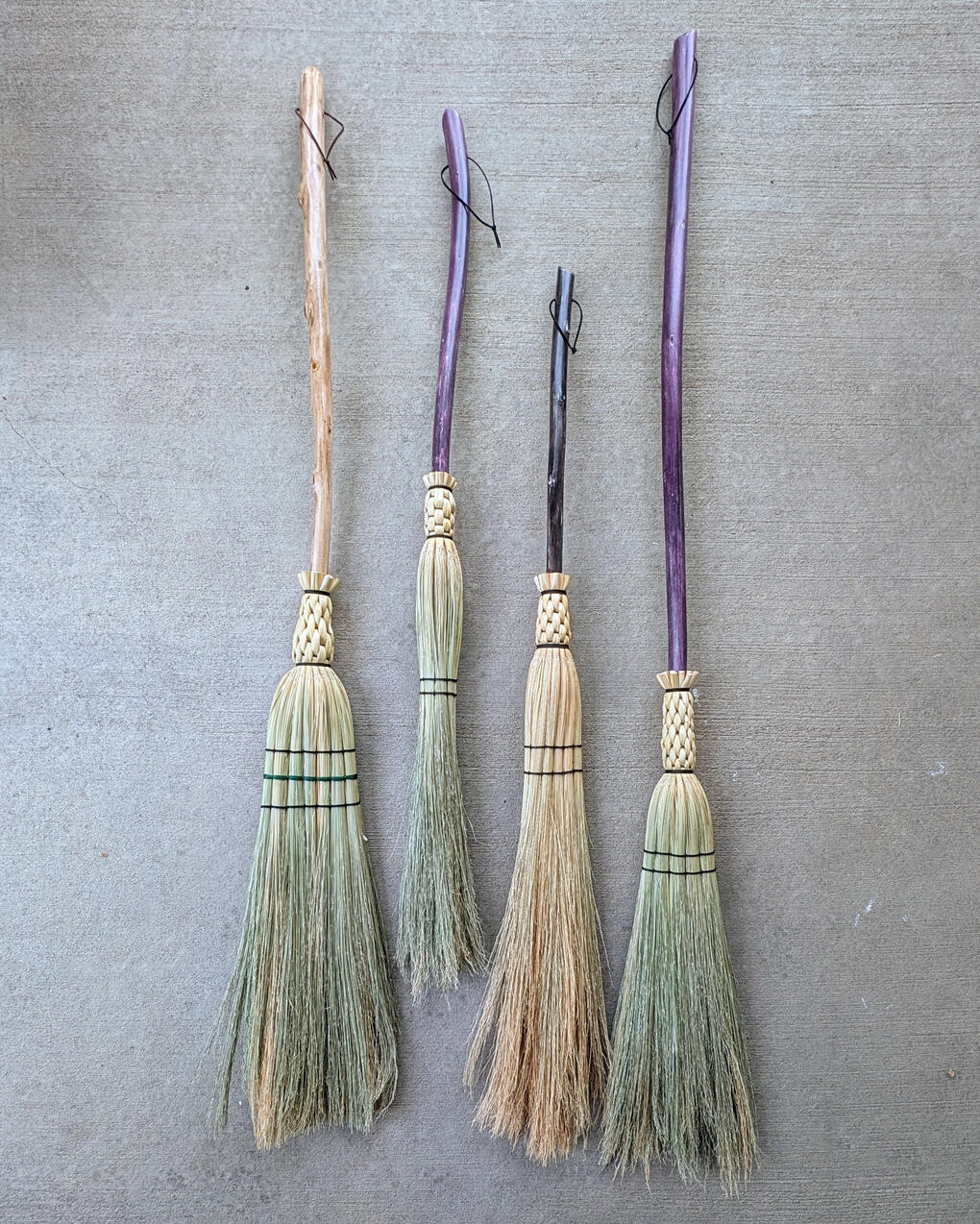 Witch's Broom Four brooms lined up on a concrete background.
